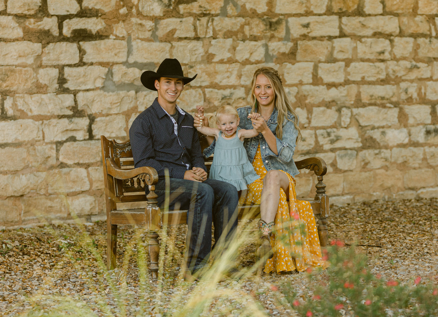 Erik & Laramie Jackson - owners of Fortitude Equine sit with their daughter on a bench